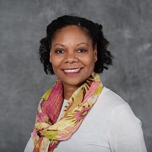 A smiling Andria Goss in front a gray background
